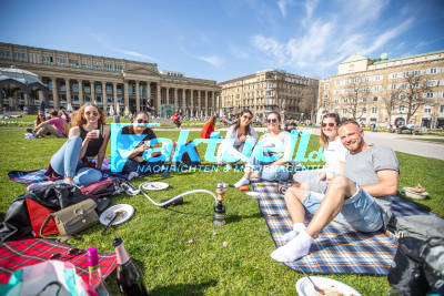 Sommerliche Temperaturen locken Stuttgarter ins Freie - Menschen genießen die Sonne auf dem Schloßplatz