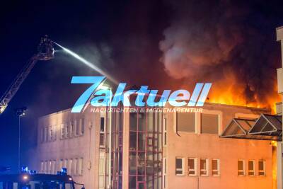Großbrand zerstört Lagerhalle und umliegende Geschäftshäuser: Explosionen zu hören - Feuerwehr kämpft gegen meterhohe Flammen