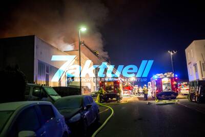 Großbrand zerstört Lagerhalle und umliegende Geschäftshäuser: Explosionen zu hören - Feuerwehr kämpft gegen meterhohe Flammen